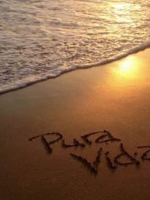 «Pura Vida» — playa al atardecer con «Pura Vida» escrito en la arena