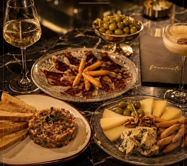 Experiencia gastronómica: tartar, ibéricos, quesos y aceitunas sobre la mesa de mármol